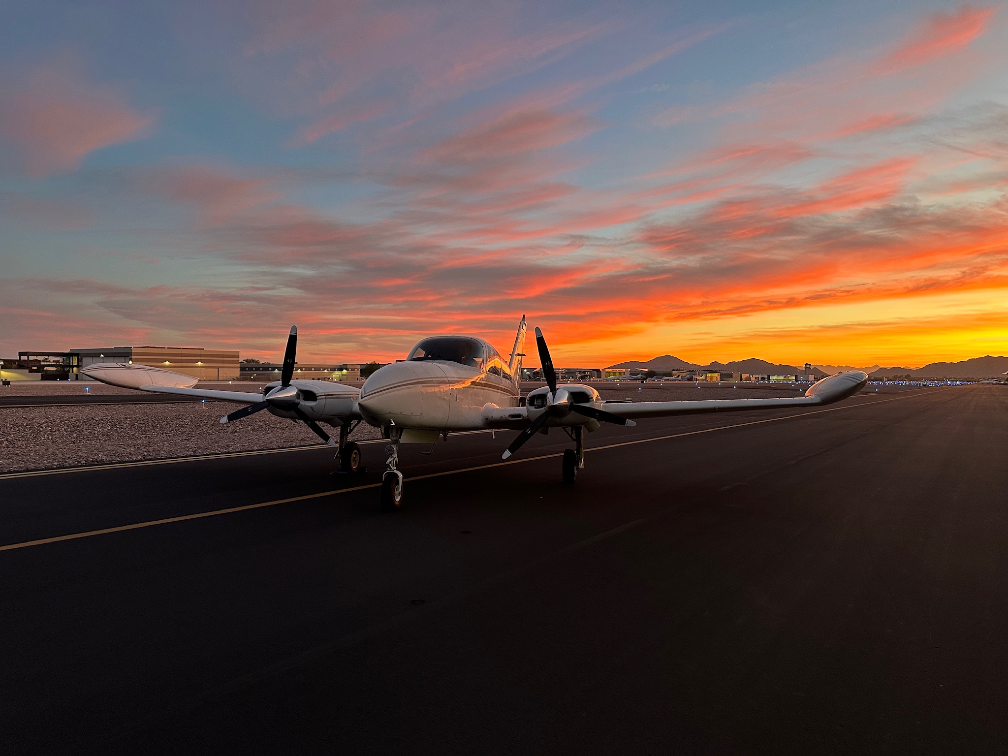 Professional twin-engine aircraft on ramp at sunset